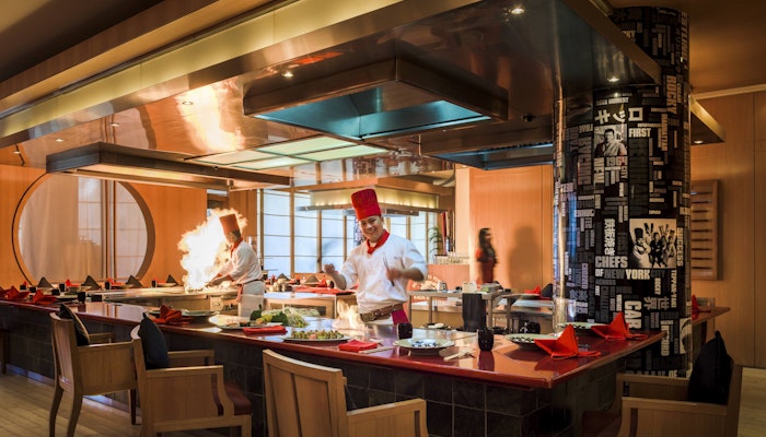 Experience live cooking at Benihana, Beach Rotana Preparing food with live flames in a vibrant open kitchen setting.
