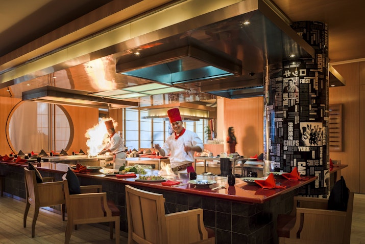 Experience live cooking at Benihana, Beach Rotana Preparing food with live flames in a vibrant open kitchen setting.