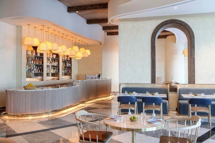 Cleo Mediterraneo restaurant interior at Hyde Hotel, showcasing a stylish bar, warm ambient lighting, and Mediterranean-inspired decor with arched mirrors and elegant seating.