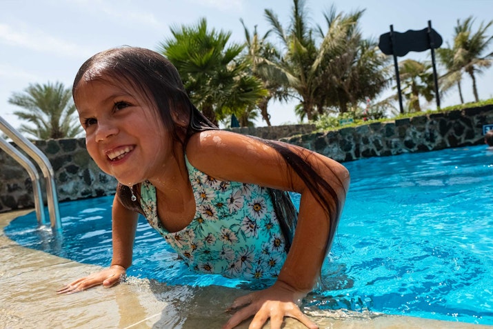 Young girl smiling and climbing out of a pool.
