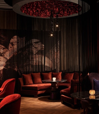 SOLA Jazz Lounge at Raffles The Palm Dubai Luxurious, dimly-lit dining lounge with plush red and velvet seating, ornate chandeliers, and atmospheric decor, creating an intimate and sophisticated setting for dinner and a show.