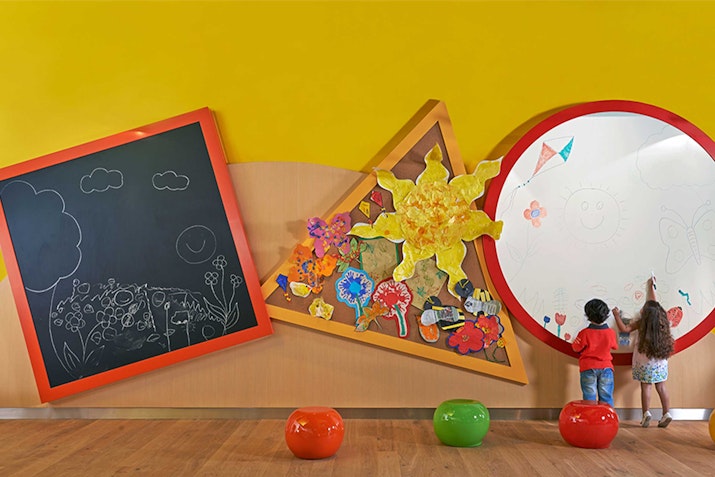 Falcons Kids' Club, Fairmont The Palm Children drawing on large interactive art walls in a colorful play area.