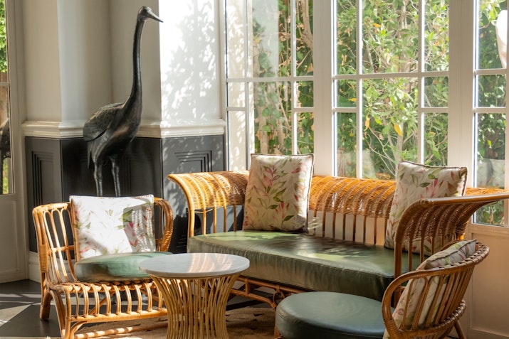 Cozy seating area with wicker furniture and large windows.