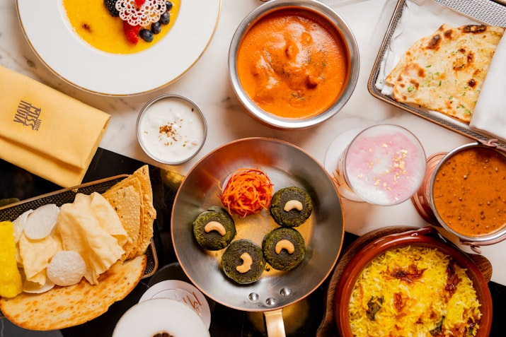 Assortment of colorful and aromatic Indian dishes on a table.
