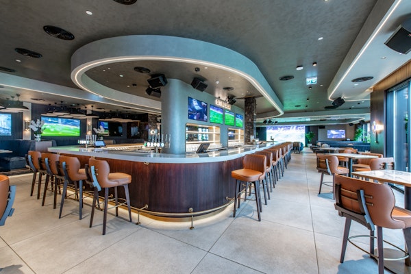 Sleek bar area with comfortable seating and multiple screens for viewing.