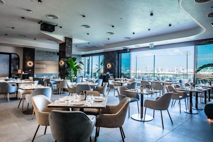 Modern dining area with large windows and stylish seating overlooking outdoor scenery.