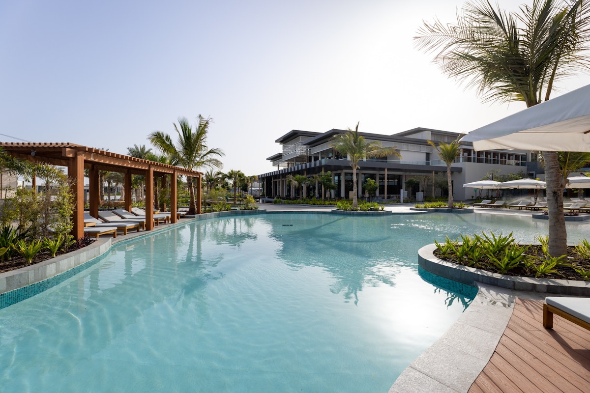 InterContinental Resorts across the UAE A pool surrounded by palm trees and shaded areas at a resort.