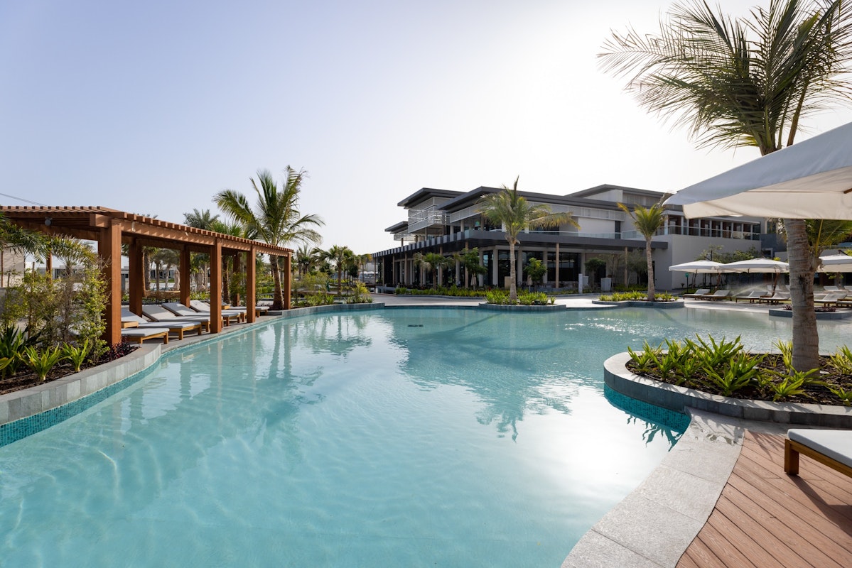 A pool surrounded by palm trees and shaded areas at a resort.