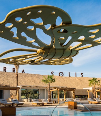 Terra Solis Dubai Modern outdoor poolside area featuring decorative shade structures and comfortable seating under a blue sky