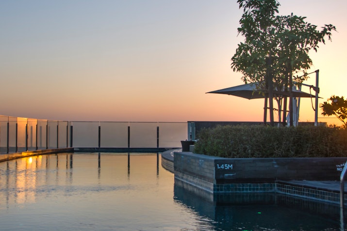 A serene infinity pool at sunset with lush greenery and a tranquil atmosphere.