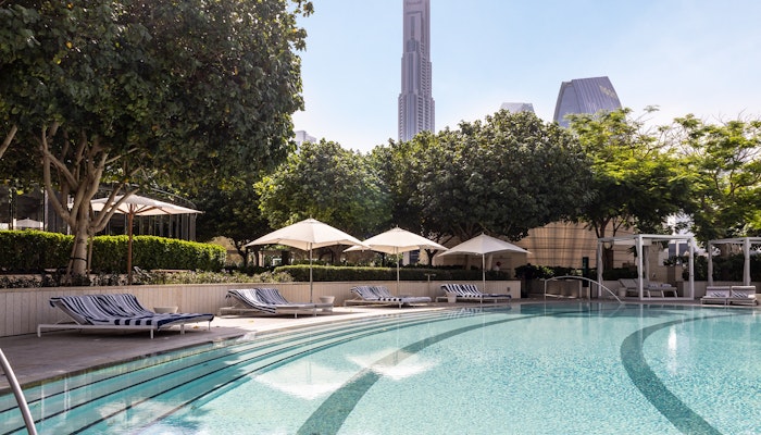 Address Sky View Infinity pool with cityscape view and shaded lounge chairs