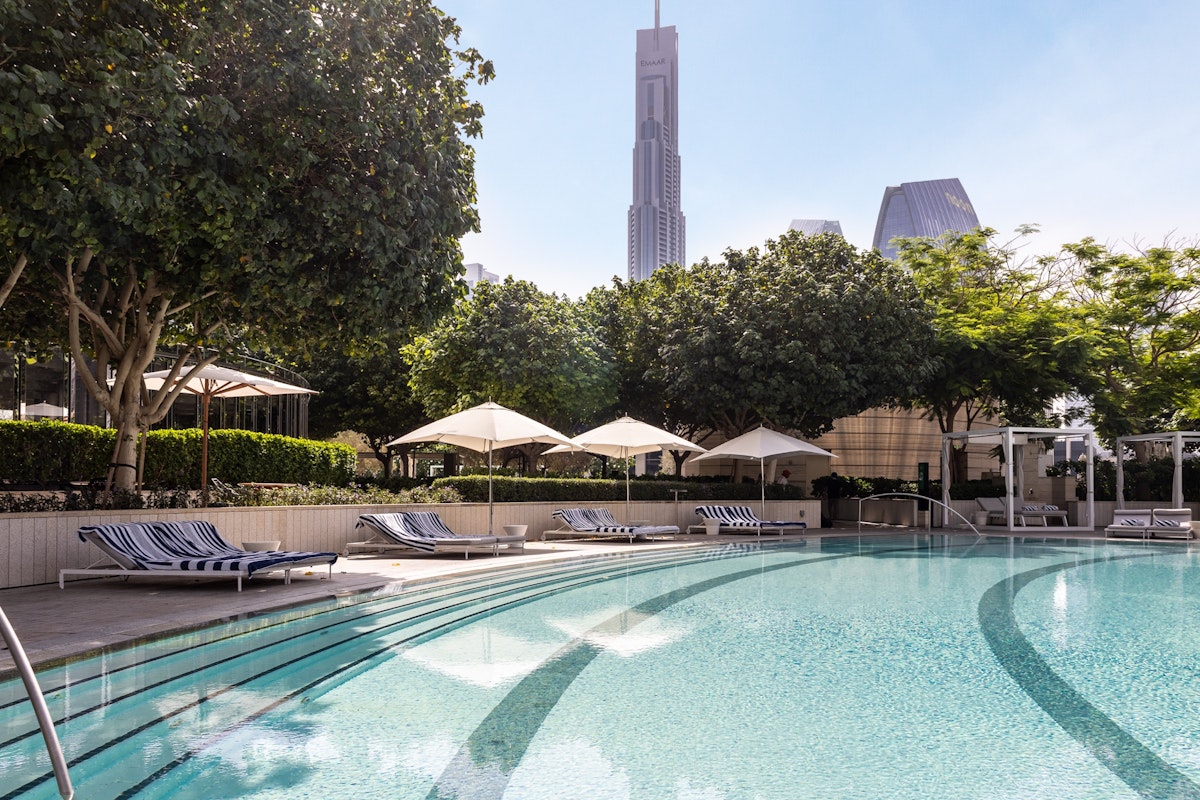 Address Sky View Infinity pool with cityscape view and shaded lounge chairs