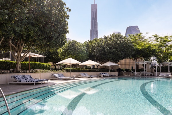 Infinity pool with cityscape view and shaded lounge chairs