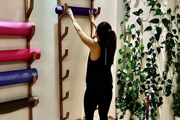 Person placing a yoga mat on a rack in a fitness studio