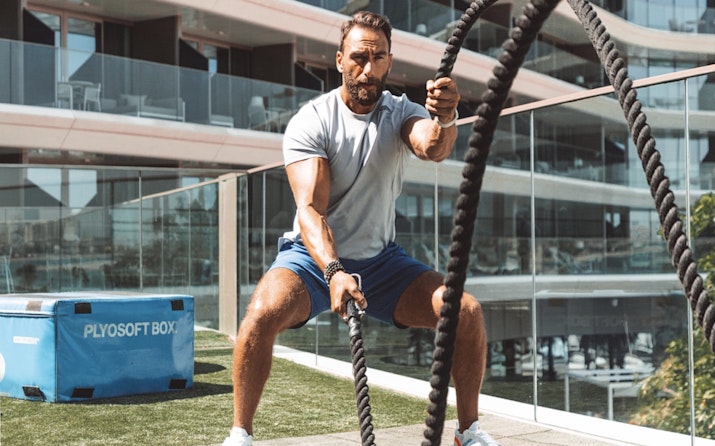 Man working out with battle ropes in a gym.