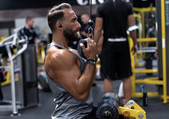 Man working out in the gym using a lat pulldown machine.