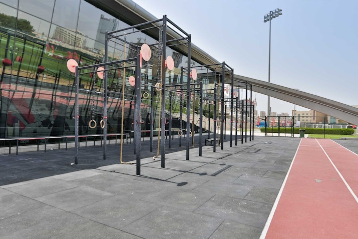 An outdoor fitness area featuring exercise bars and rings, alongside a running track.
