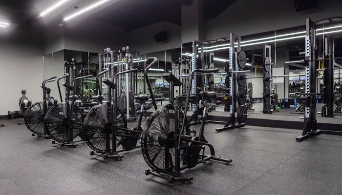 700 Padel & Fitness Hub Interior of a modern gym featuring exercise bikes and weightlifting equipment with a sleek design.