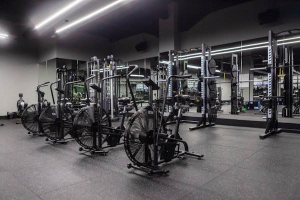 Interior of a modern gym featuring exercise bikes and weightlifting equipment with a sleek design.