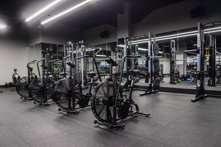 Interior of a modern gym featuring exercise bikes and weightlifting equipment with a sleek design.