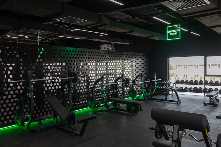 GIGAFIT Gym area with a variety of free weights, including dumbbells, barbells, and benches.