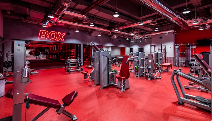 Fitness First, The Palm Dubai A red-themed gym with various workout machines and equipment, including a "BOX" sign on the wall.
