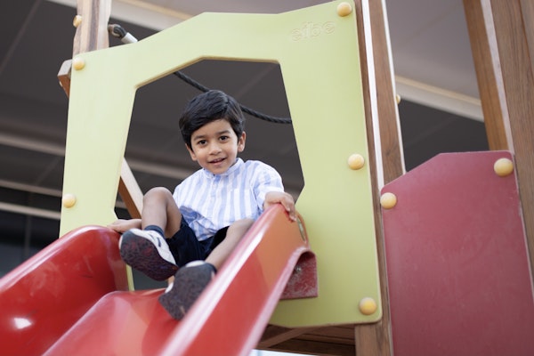 Get free access to these kids’ Clubs A child sliding down a colorful playground slide.
