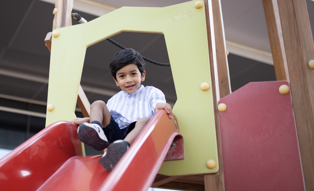 A child sliding down a colorful playground slide.
