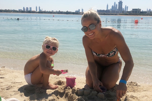 Mother and child playing in the sand at the beach.
