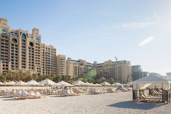 Fairmont The Palm Resort buildings with beach loungers and cabanas on the sand
