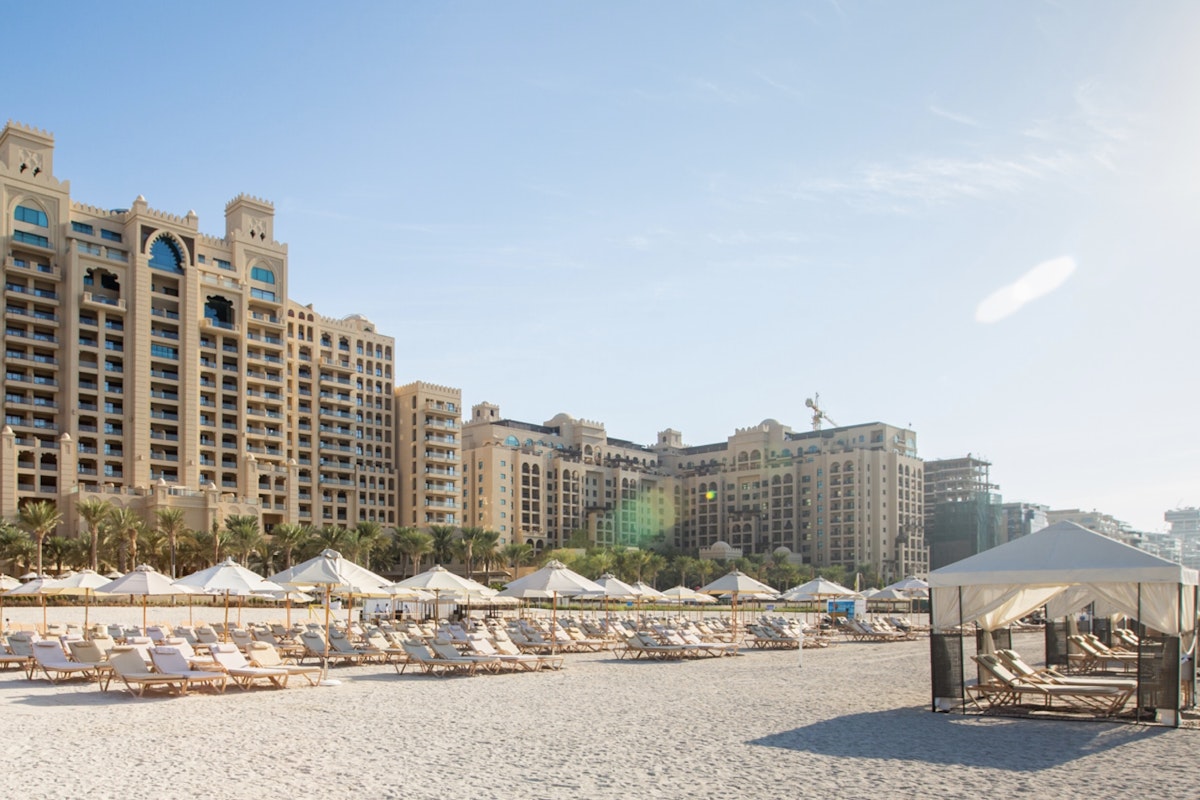 Fairmont The Palm Resort buildings with beach loungers and cabanas on the sand