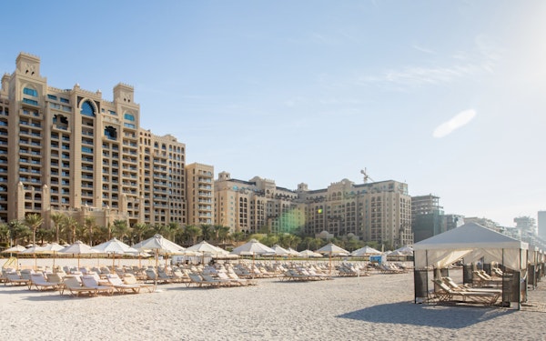 Resort buildings with beach loungers and cabanas on the sand