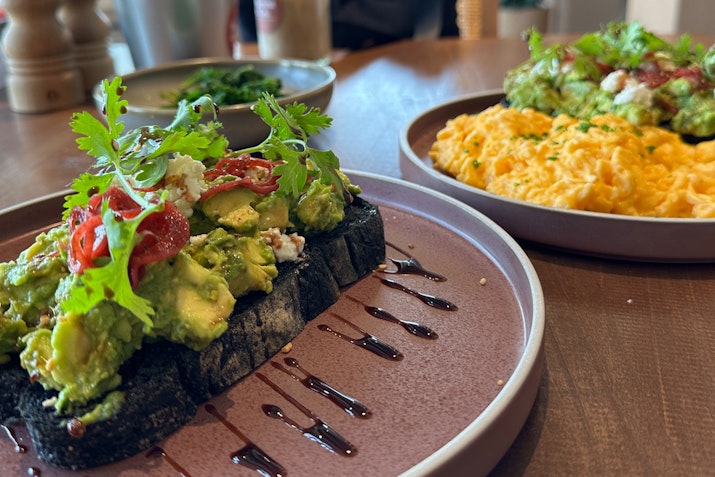 Post-Workout Breakfast Bliss Avocado toast with toppings and scrambled eggs on plates.