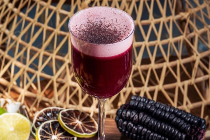 Signature Peruvian Cocktail: A Fusion of Flavors. Vibrant purple drink garnished with a dark powdery topping