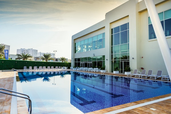 Outdoor pool area with lounge chairs and a modern building in the background.