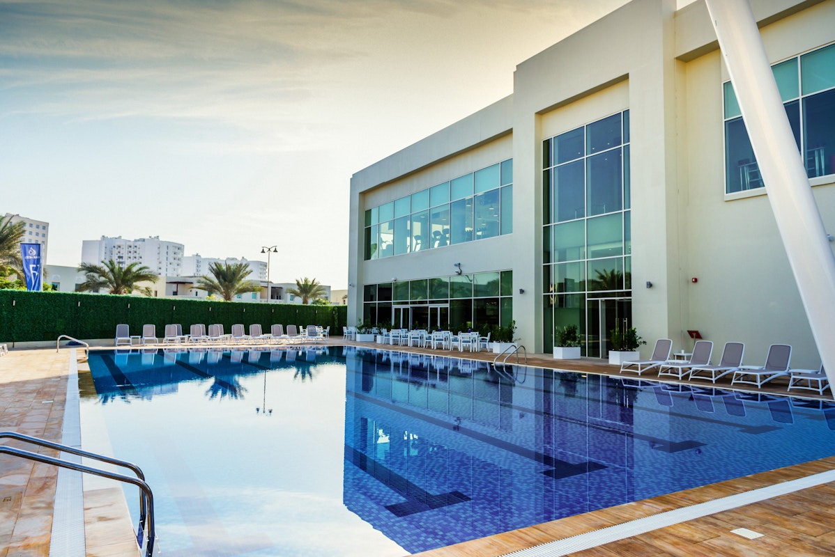 Outdoor pool area with lounge chairs and a modern building in the background.