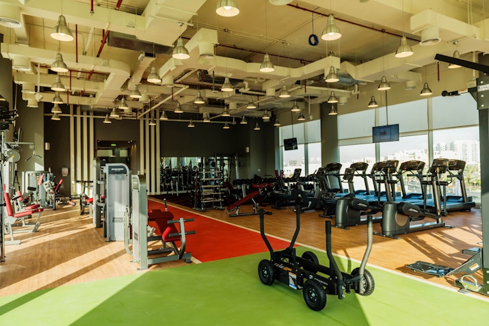 Spacious gym with modern fitness equipment, including treadmills, weights, and a functional training area.