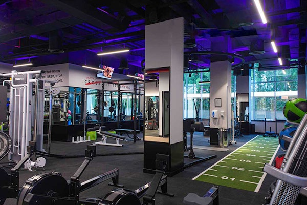 A modern gym interior featuring various fitness equipment, bright lighting, and a turf area for workouts.