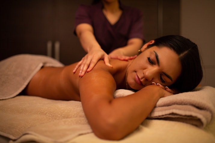 A woman receiving a back massage in a spa setting.