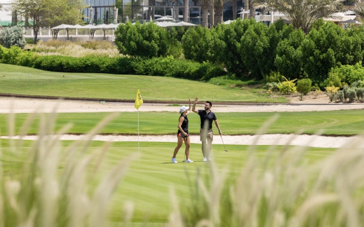JA Lake View Couple playing golf on a lush green course