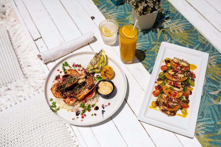 Grilled shrimp dish and colorful salad with fresh juice on a table.