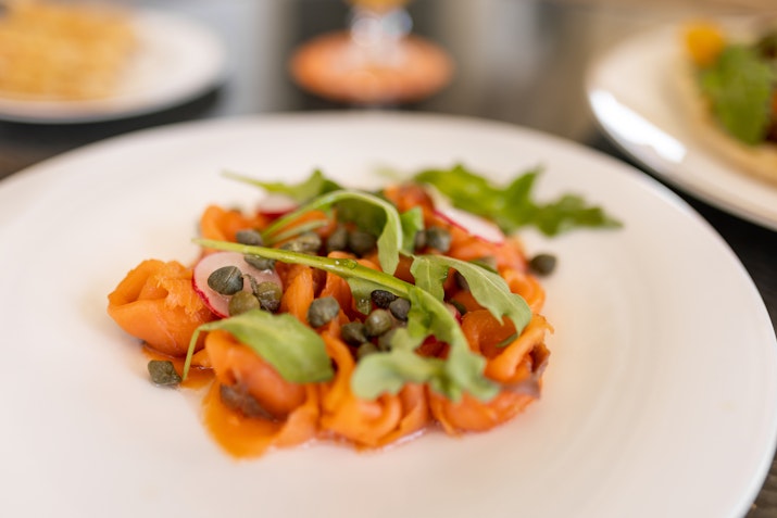 Plate of smoked salmon garnished with arugula and capers