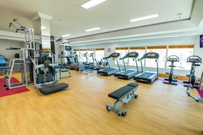 Gym interior with various workout equipment and cardio machines.