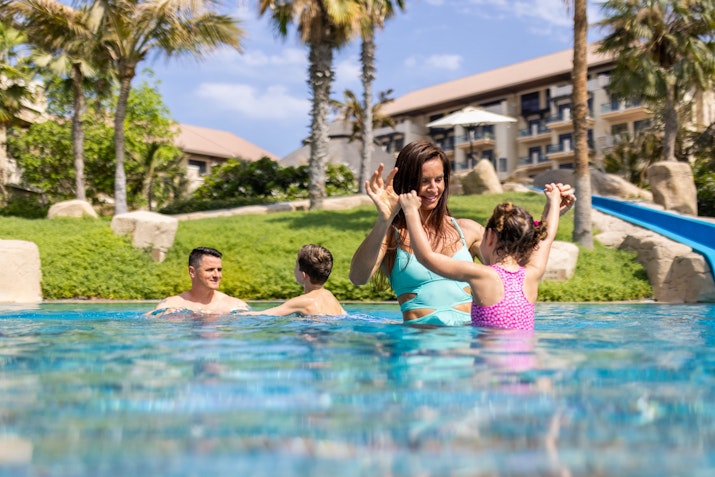 Mother playing with children in a resort pool.