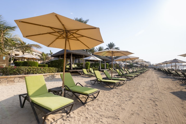 Row of lounge chairs with umbrellas on a sandy beach