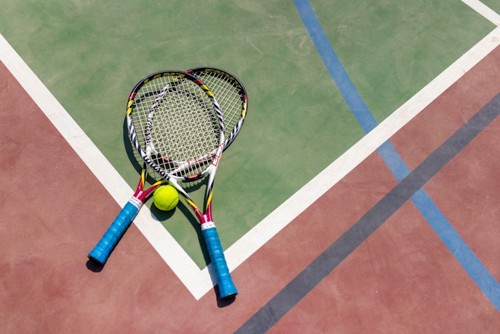 Two tennis rackets and a ball on a court