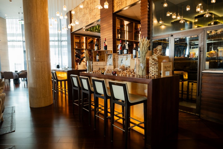 Dimly lit and intimate bar featuring high stools and a mirrow on the right.