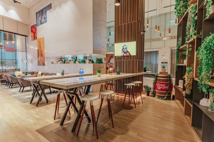 Interior view of restaurant featuring a modern, vibrant workspace with high tables and greenery.