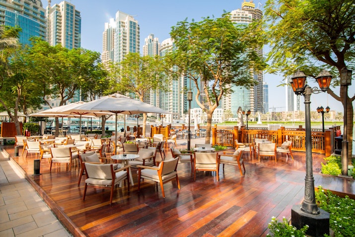 The Palace Downtown Outdoor restaurant seating with wooden flooring and umbrellas.