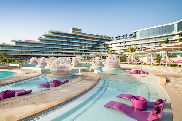 Modern resort pool area with domed seating and pink lounge chairs